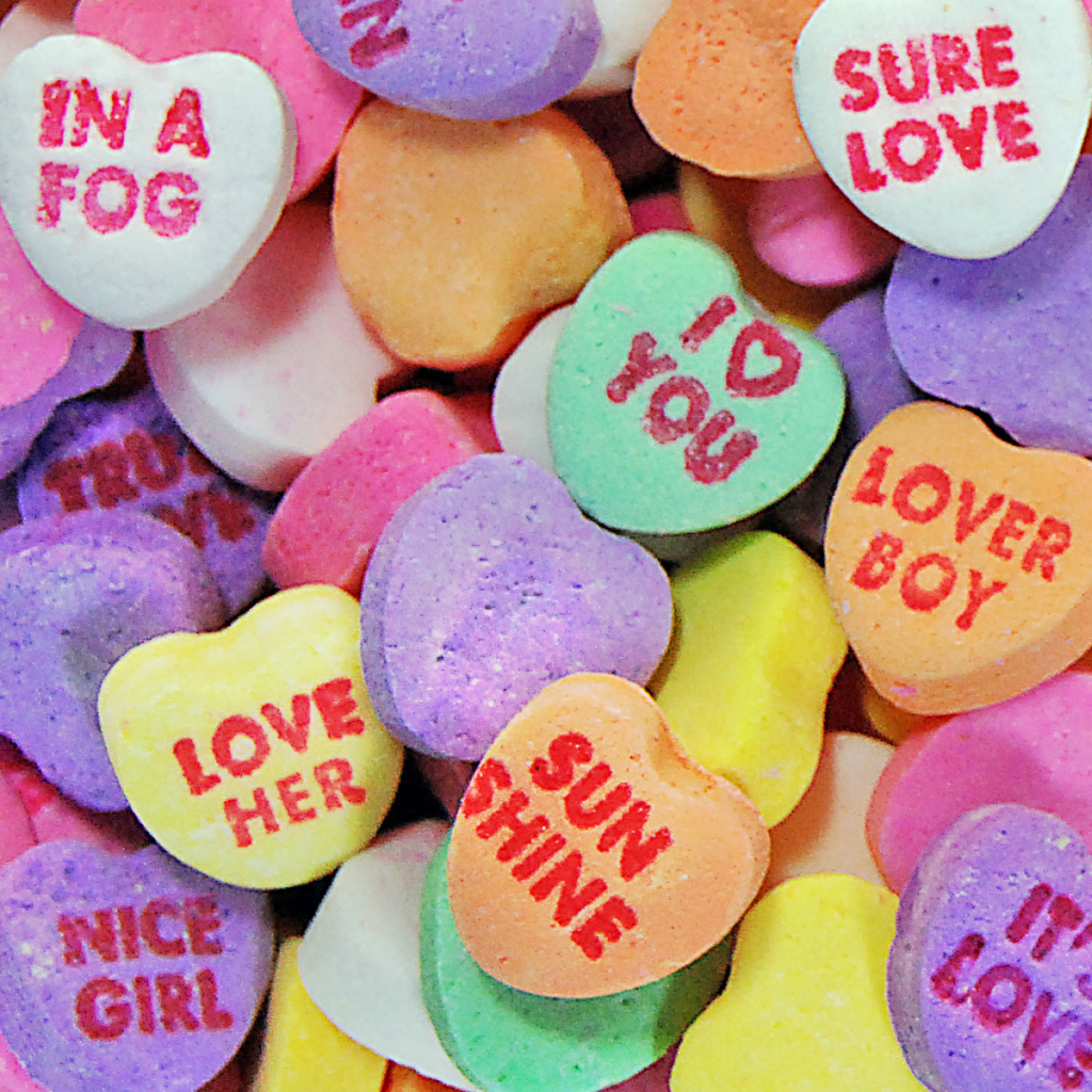 Valentine's themed candy hearts with text on them such as "love her" and "sunshine".