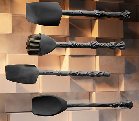 Four silicone dark grey baking utensils with ornate handles designed as wands. 